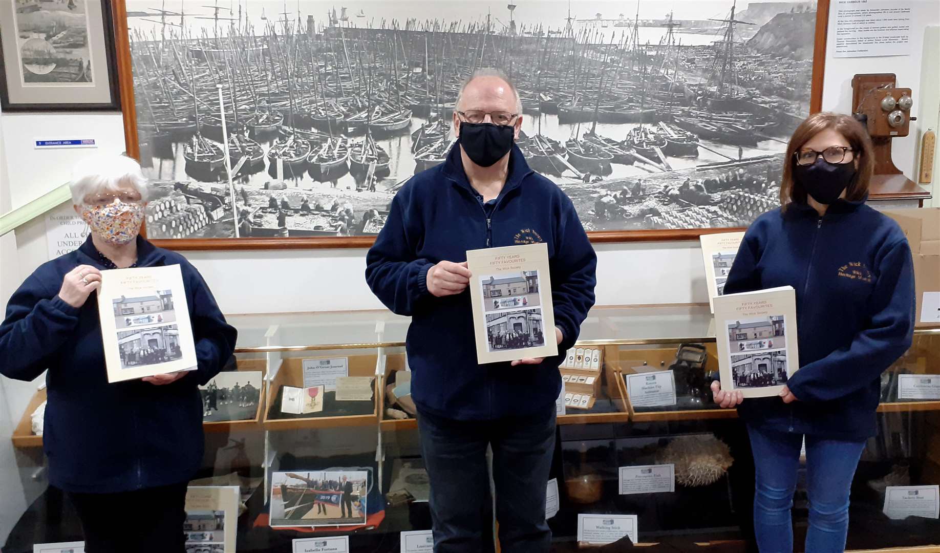 Wick Society trustee Ian Leith with his wife Doreen (left), a volunteer who compiled and edited Fifty Years, Fifty Favourites, and vice-chairperson Valerie Amin, holding copies of the 50th anniversary book in the museum earlier this year.