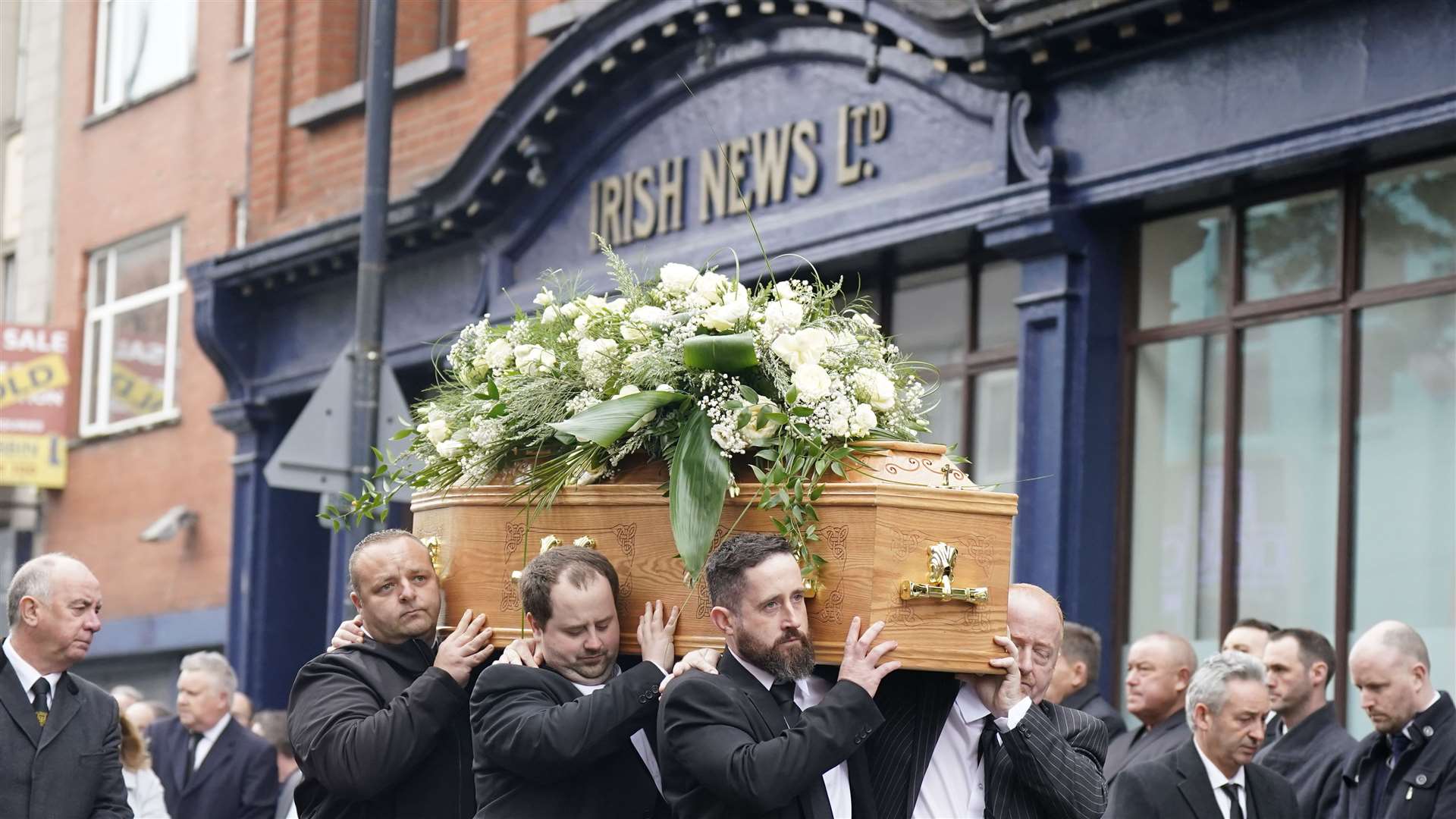 Russell’s coffin is taken past the offices of the Irish News (Niall Carson/PA)