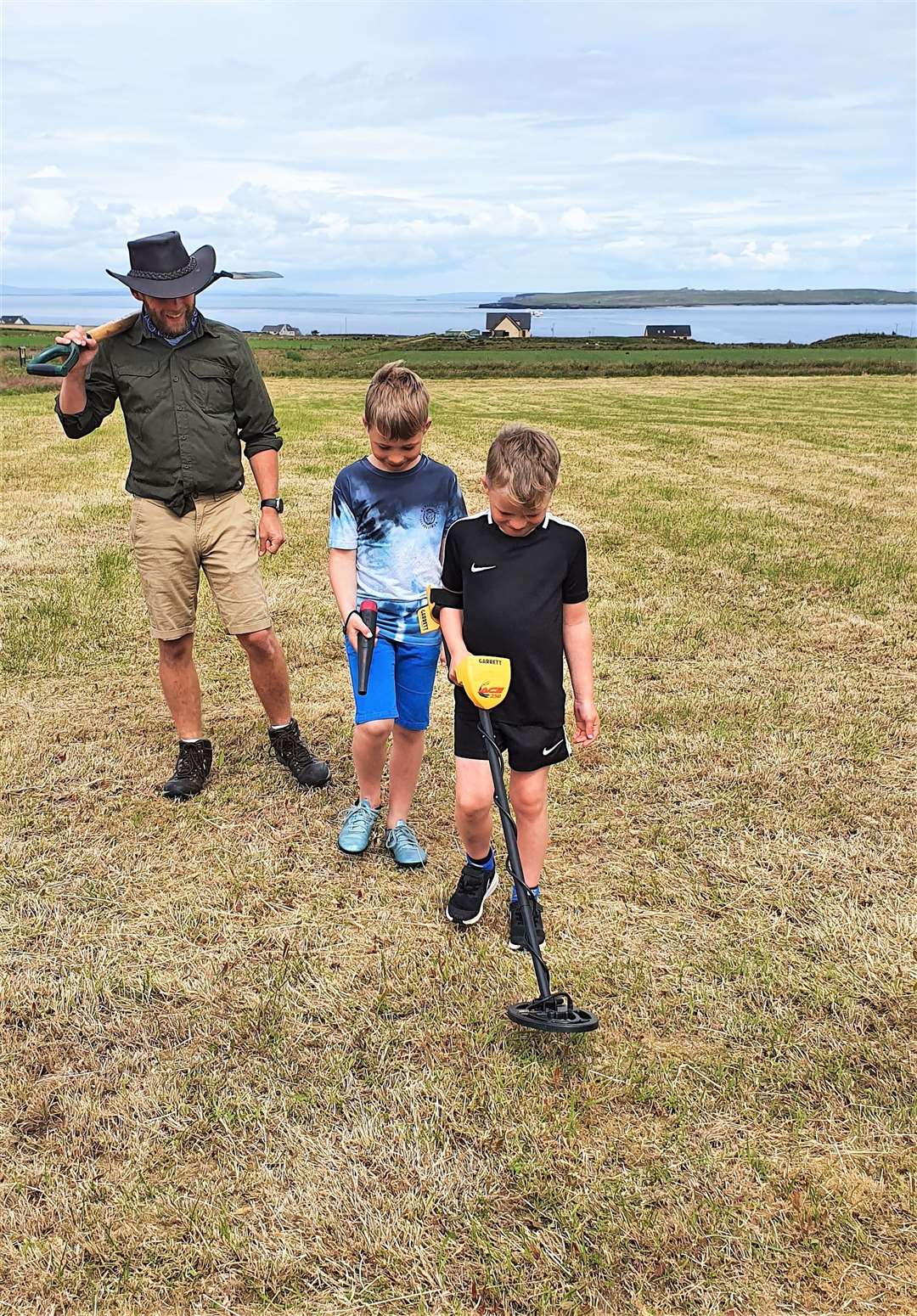 Chris Aitken with his sons Finlay, with metal detector, and Callum in the field where they found the badge.