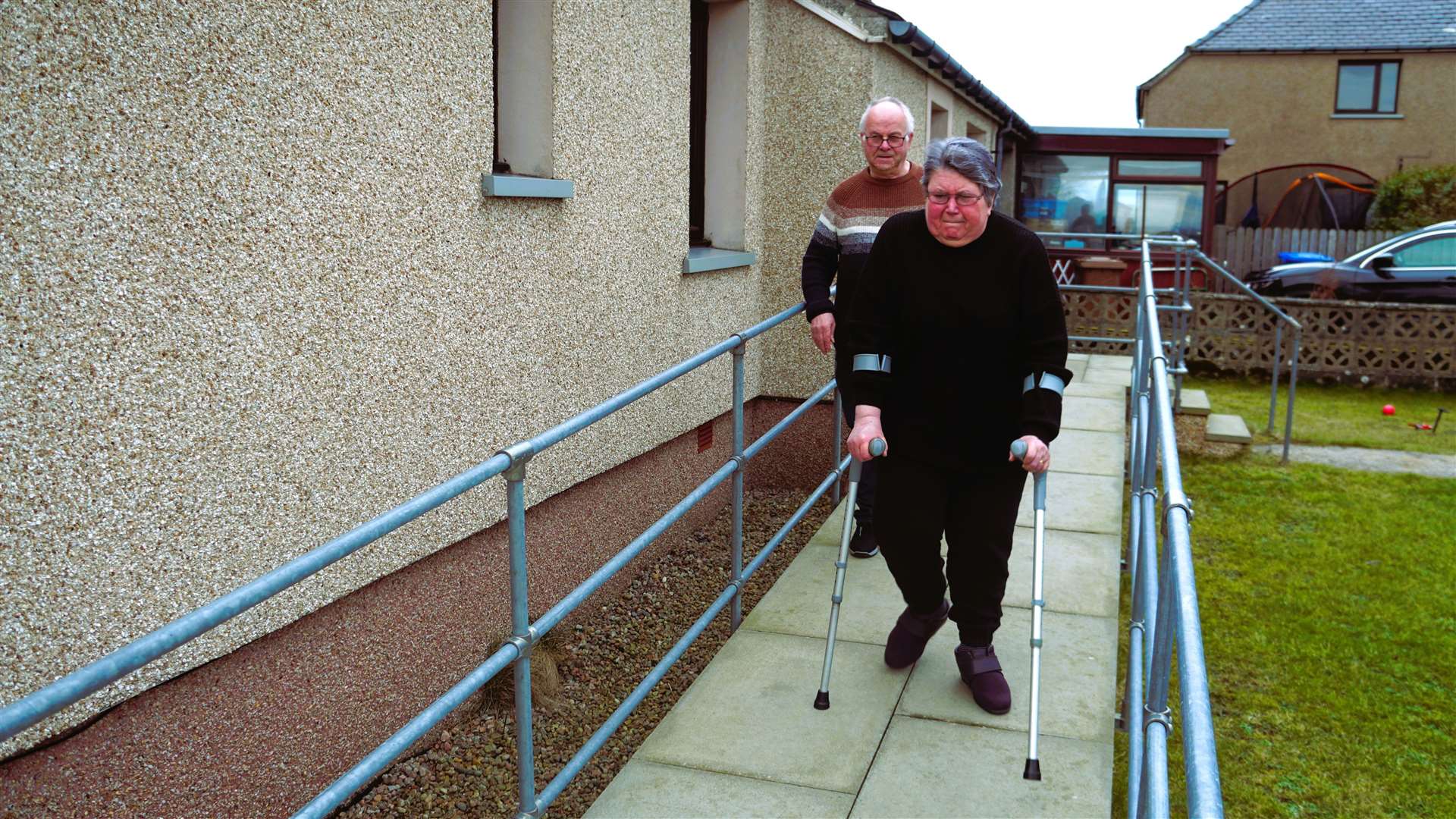 Lynne with her husband Robin as they exit their home in Keiss. She also uses a wheelchair which she says is unstable on the potholed road. Picture: DGS