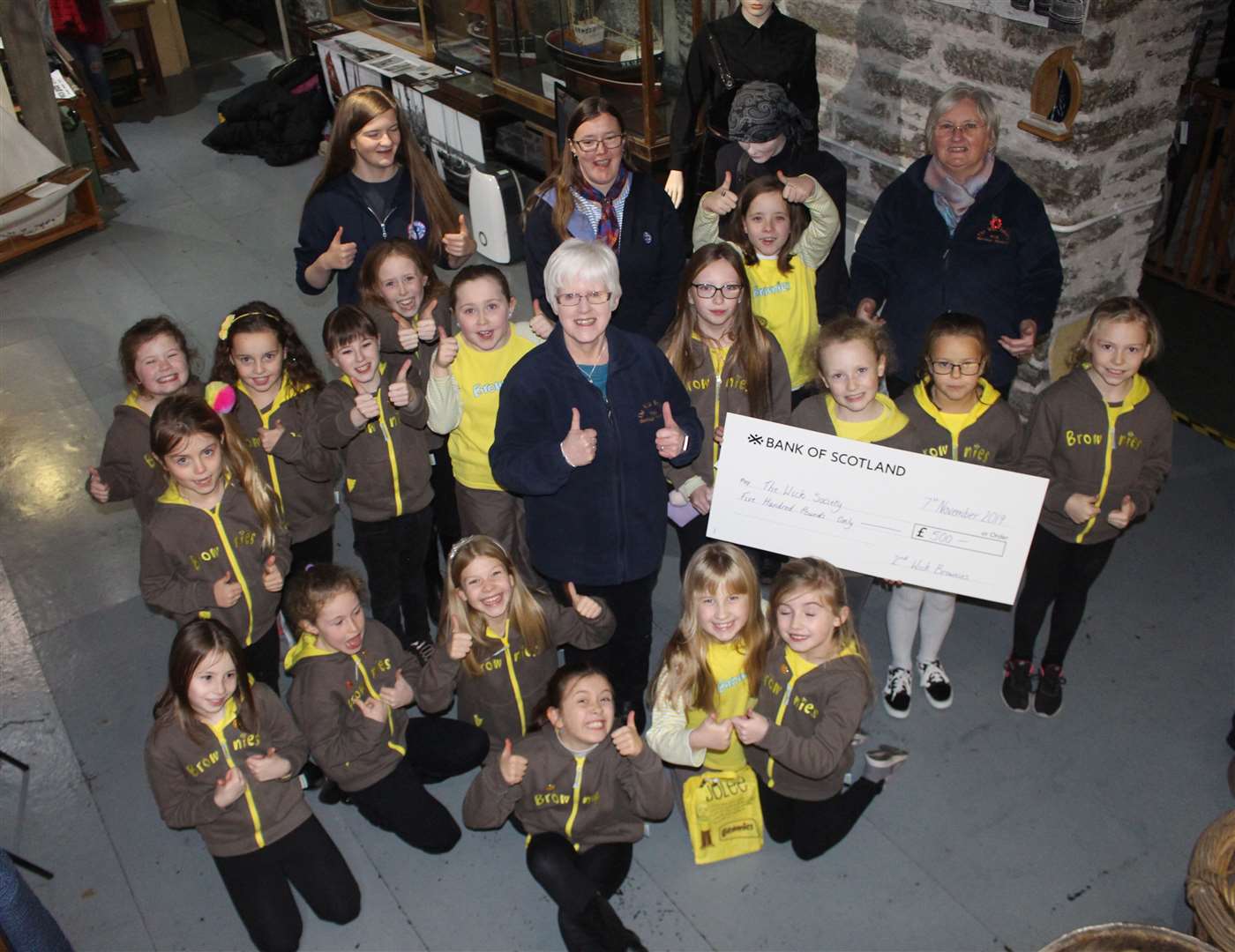 Volunteer Doreen Leith accepts a cheque for £500 on behalf of Wick Heritage Museum from the 2nd Wick Brownies. The money was raised by a sponsored walk around Pulteneytown.