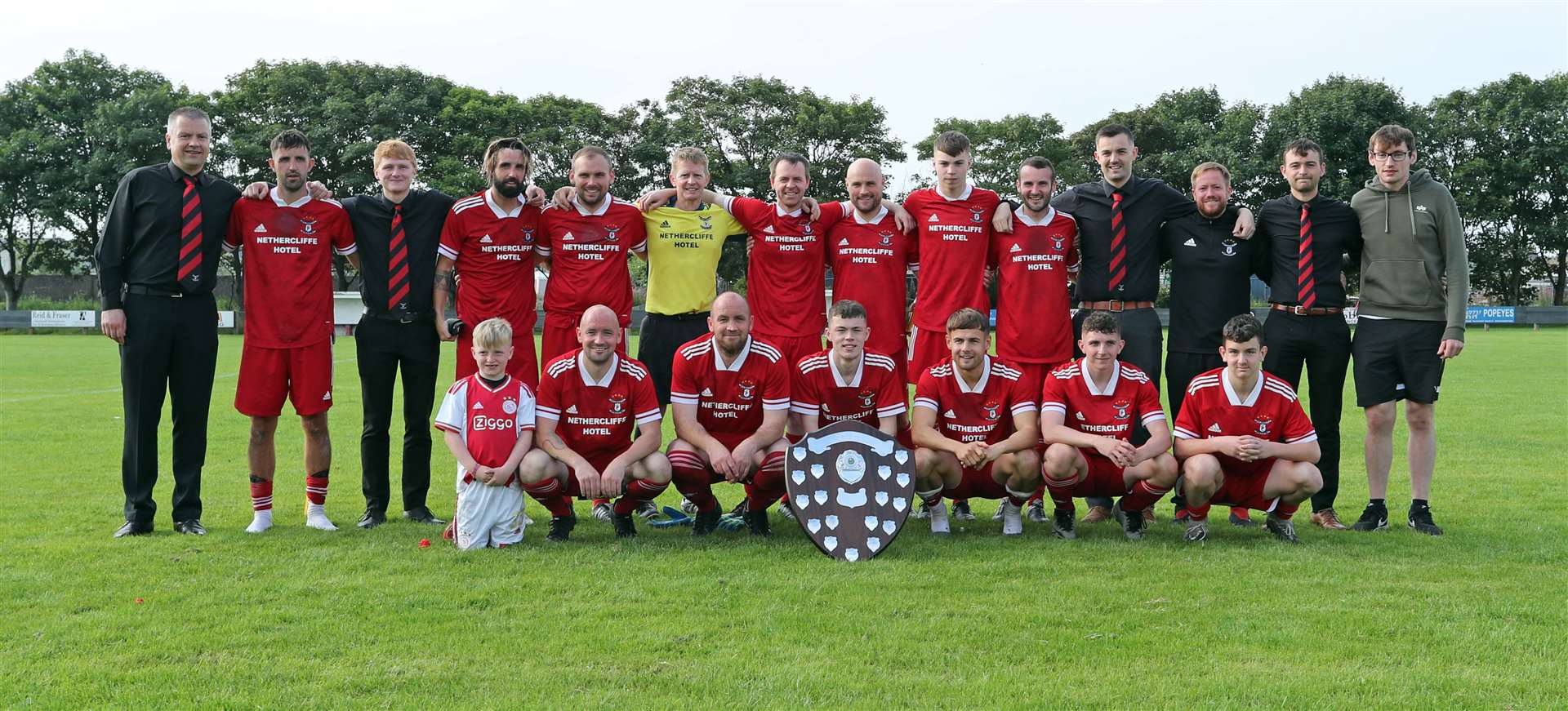 Wick Groats players and management with the David Allan Shield. The post-match celebrations were subdued following the serious injury to Liam Bremner. Picture: James Gunn