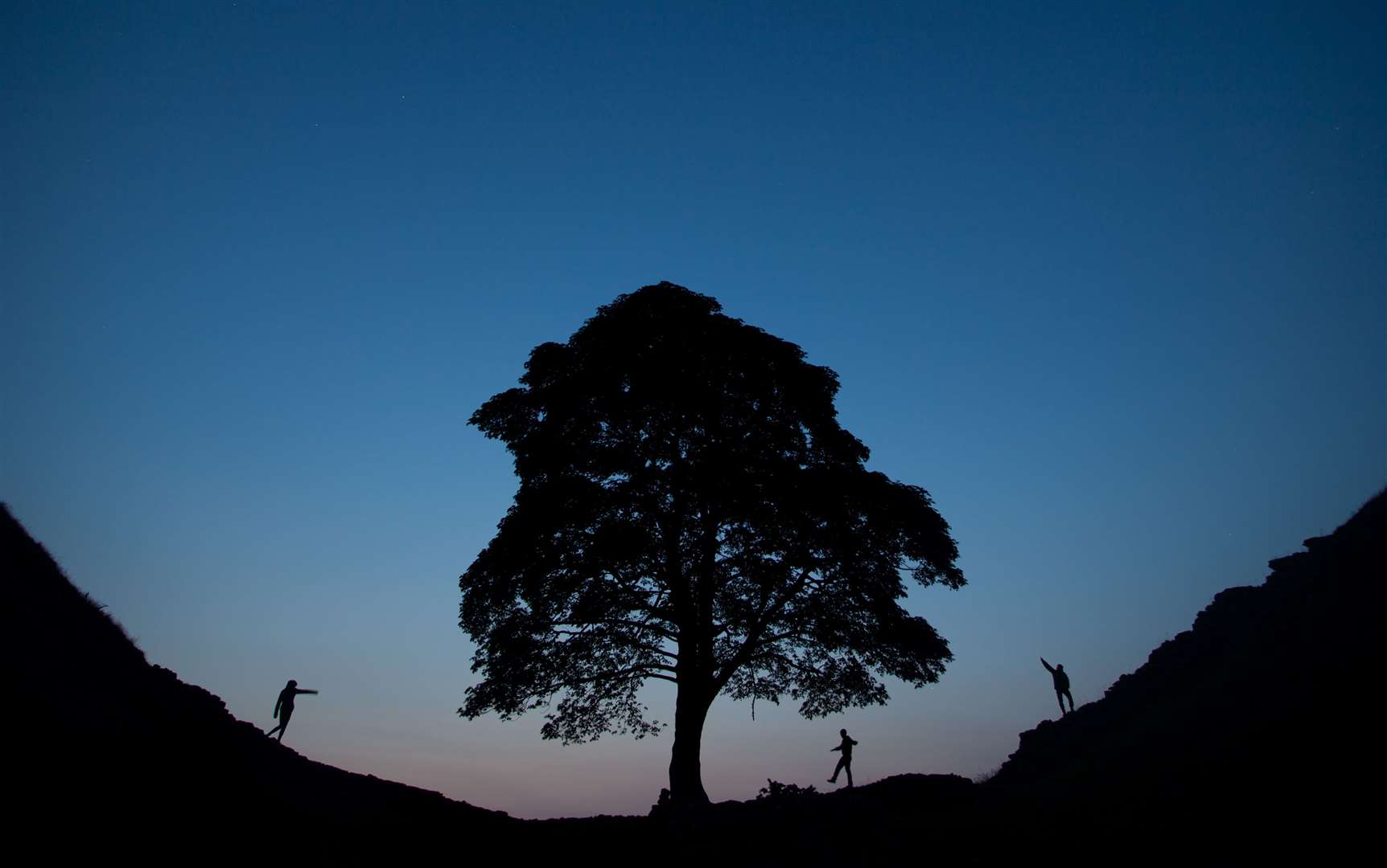 People take an evening walk at Sycamore Gap in Northumberland (Tom White/PA)