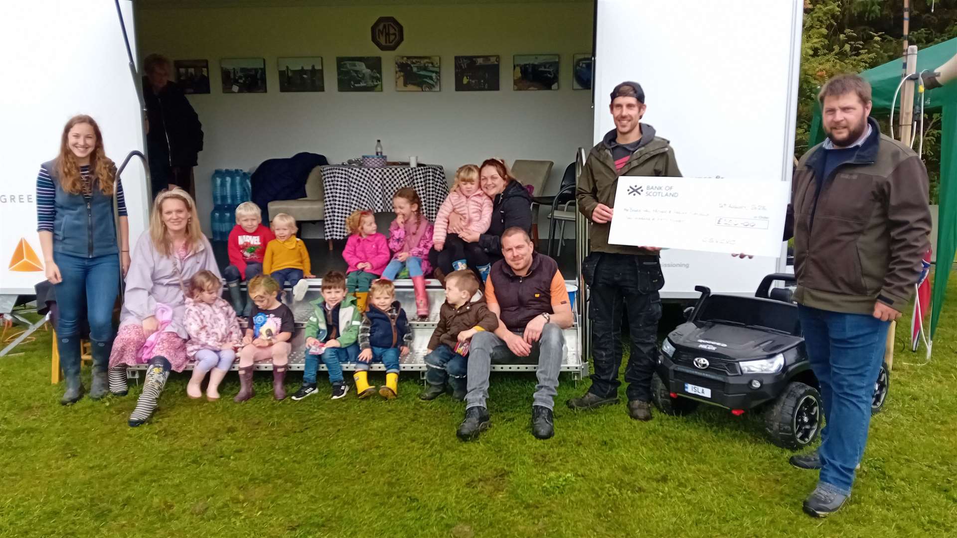 James Green vice chairman of the Caithness and Sutherland Vintage and Classic Vehicle Club presents a cheque for £250 to Fergus Silverwood, to be shared by the young Bower Bumble Bees and the Bower Busy Bees with several club youngsters looking on. Picture: Willie Mackay