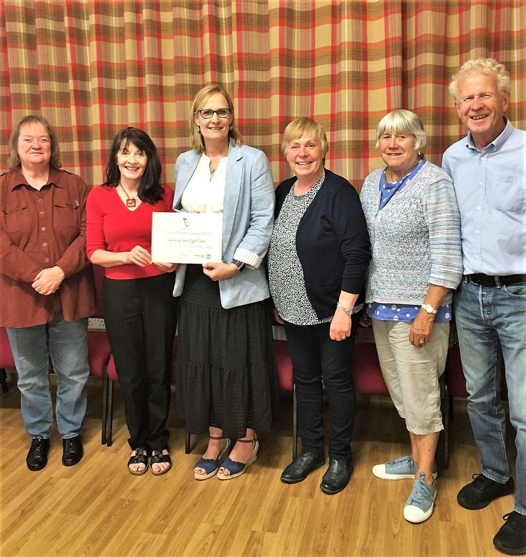 Deirdre Aitken, with some of the Hearing and Sight Care volunteers, receives the Volunteer Friendly Award from Catherine Patterson (in red top) of Caithness Voluntary Group.
