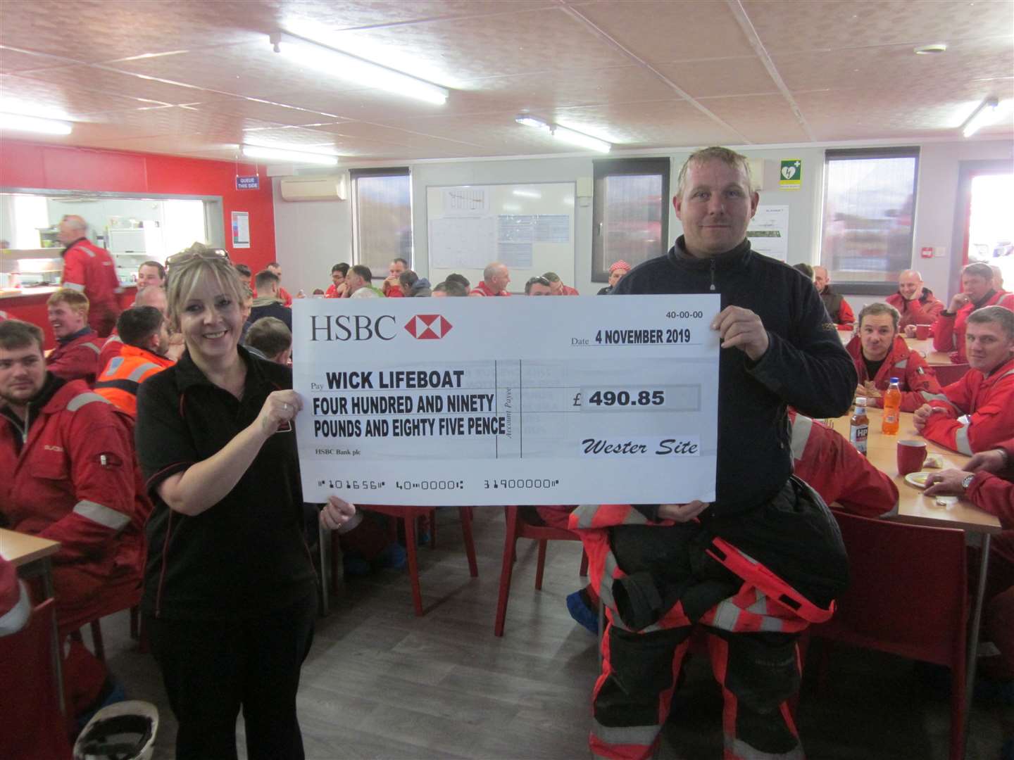 Subsea 7 canteen supervisor Lillian Mulraine presents cheque for £490.85 to Wick lifeboat crew member Stuart Campbell.