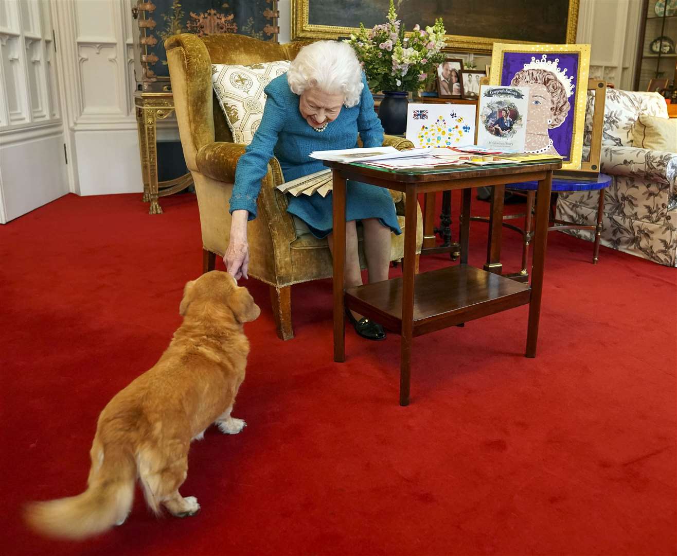 The Queen with one of her dogs, a Dorgi called Candy, as she viewed a display of memorabilia from her Golden and Platinum Jubilees in the Oak Room at Windsor Castle (Steve Parsons/PA)