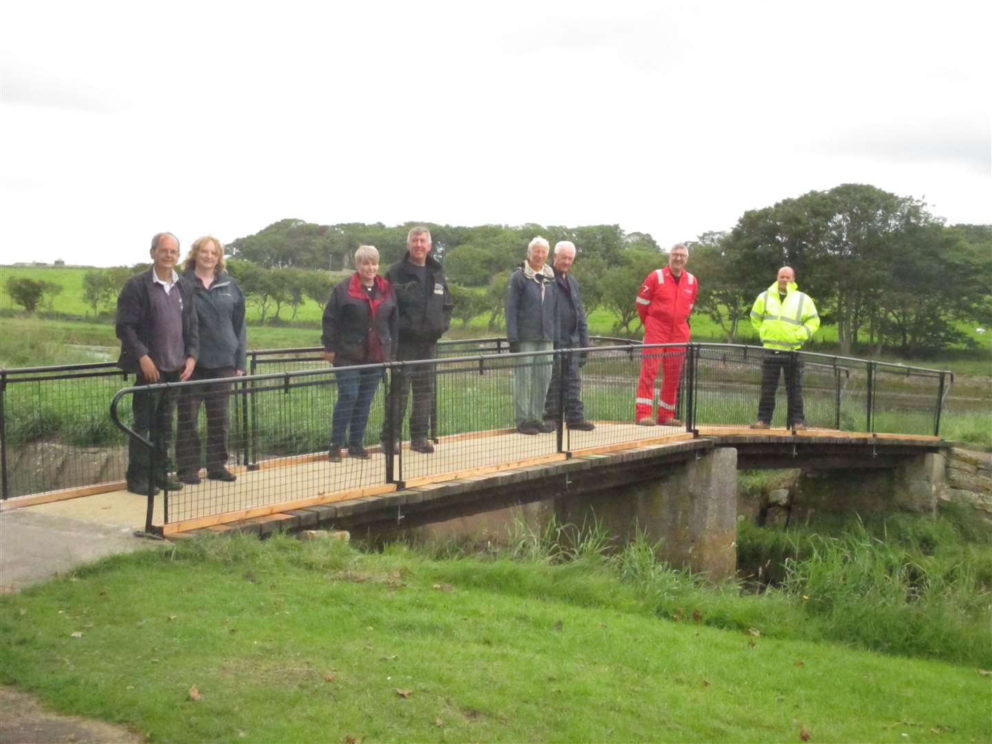 Some of the team of volunteers standing on the smaller of the two riverside footbridges that are being upgraded.