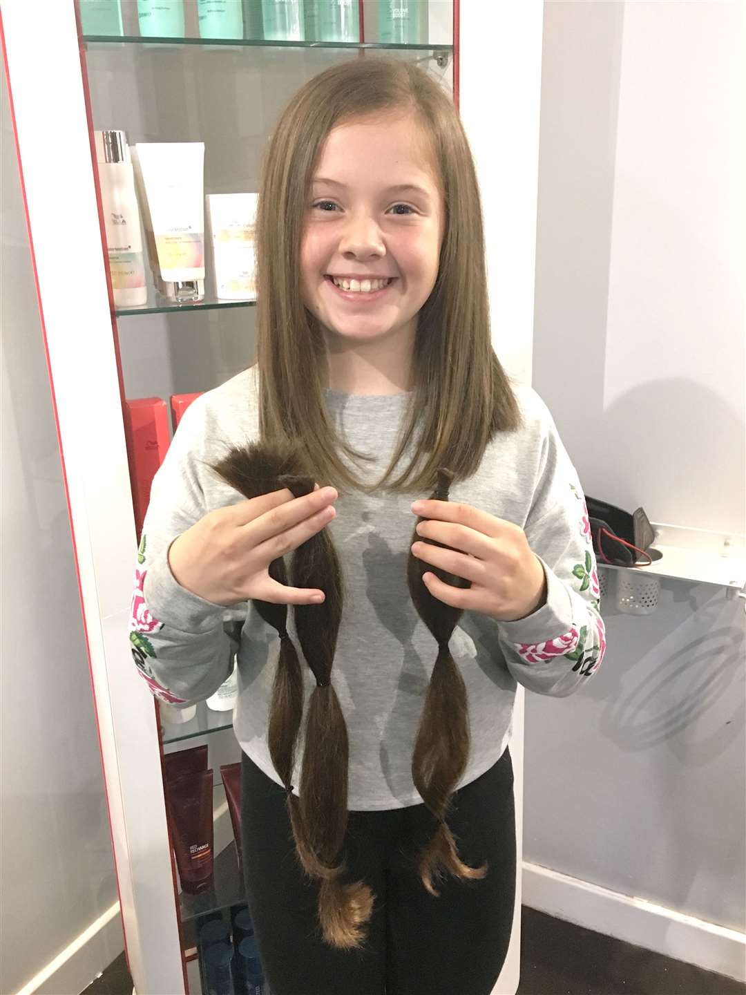 Chloe holds the braids that are ready to be sent away for sick children. Seventeen inches were chopped off.