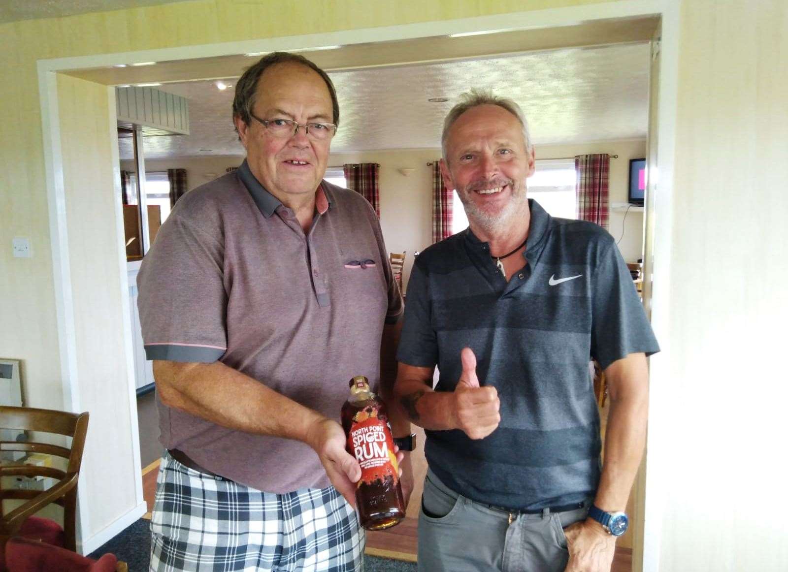 Mike Halliday handing a bottle of North Point Spiced Rum to Donald Mowat (right) after the latter won the nearest-the-pin prize at the Senior Stableford competition last week.