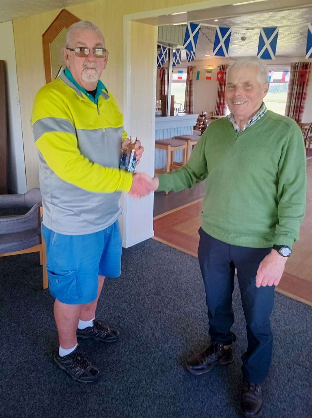 Pete McCartney (left) receives the nearest-the-pin prize courtesy of sponsors North Point Distillery from seniors convener Sandy Chisholm.
