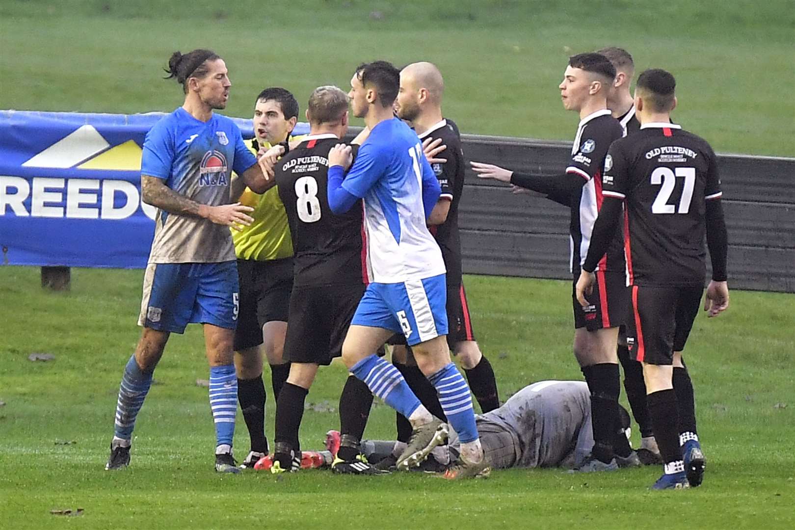 Referee Calum Haswell pulls Benburb's Ryan Docherty away from Wick players after home keeper Graeme Williamson had taken a kick to the head from Lewis Lovering. Picture: Mel Roger