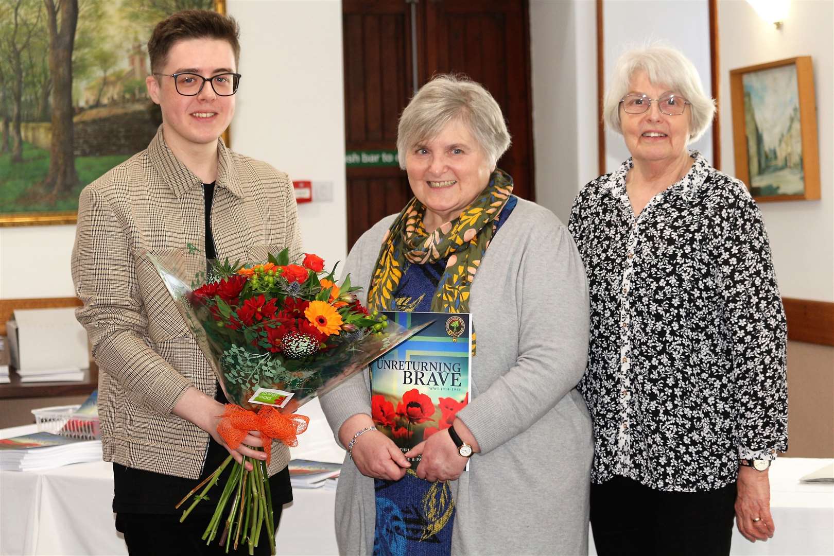 It's smiles all round as Kathy, at centre, is presented with flowers by Jayden Alexander and Anna Rogalski from Caithness Family History Society. Picture: Eswyl Fell