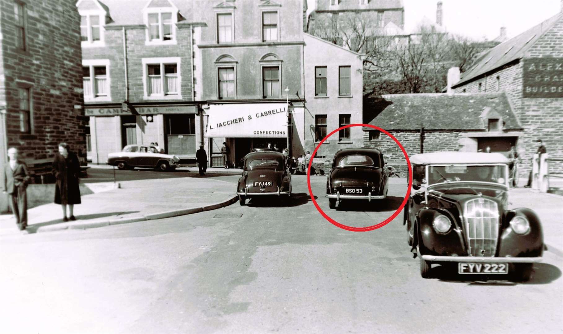 The Austin car is highlighted with a red circle and is heading towards Cabrelli's cafe.
