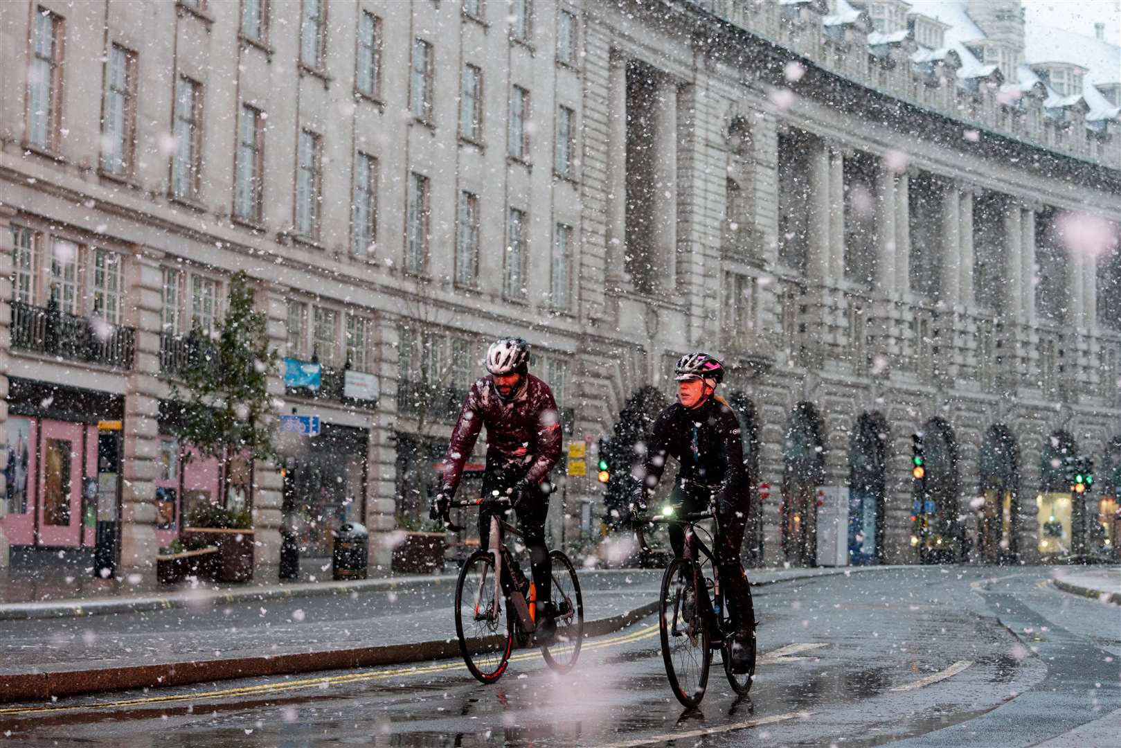 Cyclists ride through falling snow on Regent Street (Dominic Lipinski/PA)