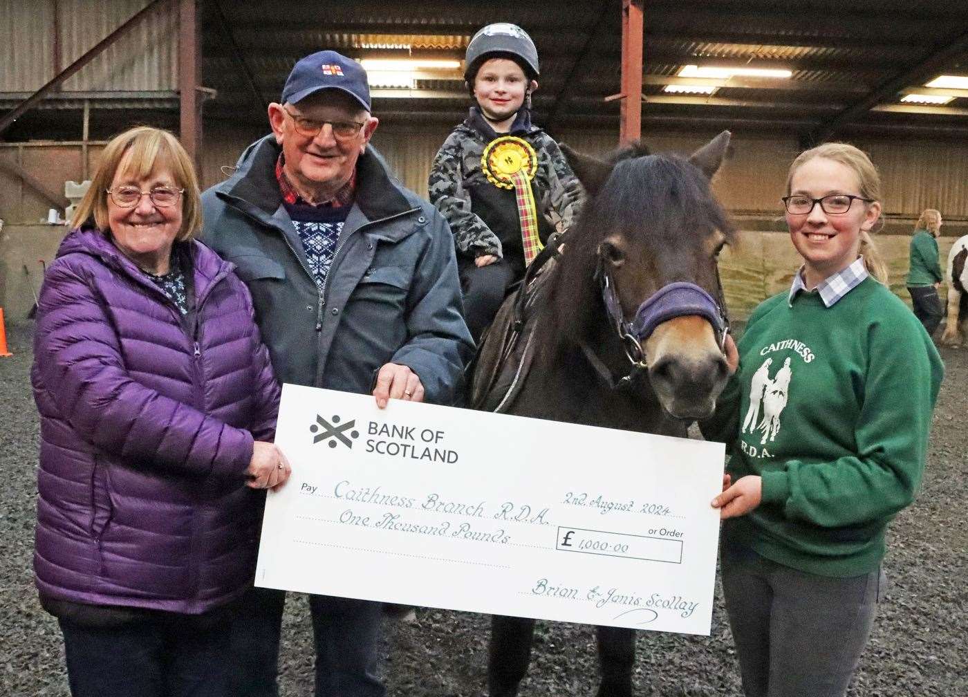 Janis and Brian Scollay presenting a cheque for £1000 to Marty Mackenzie, their grandson, and Megan Gillon, newly qualified group coach. Picture: Neil Buchan