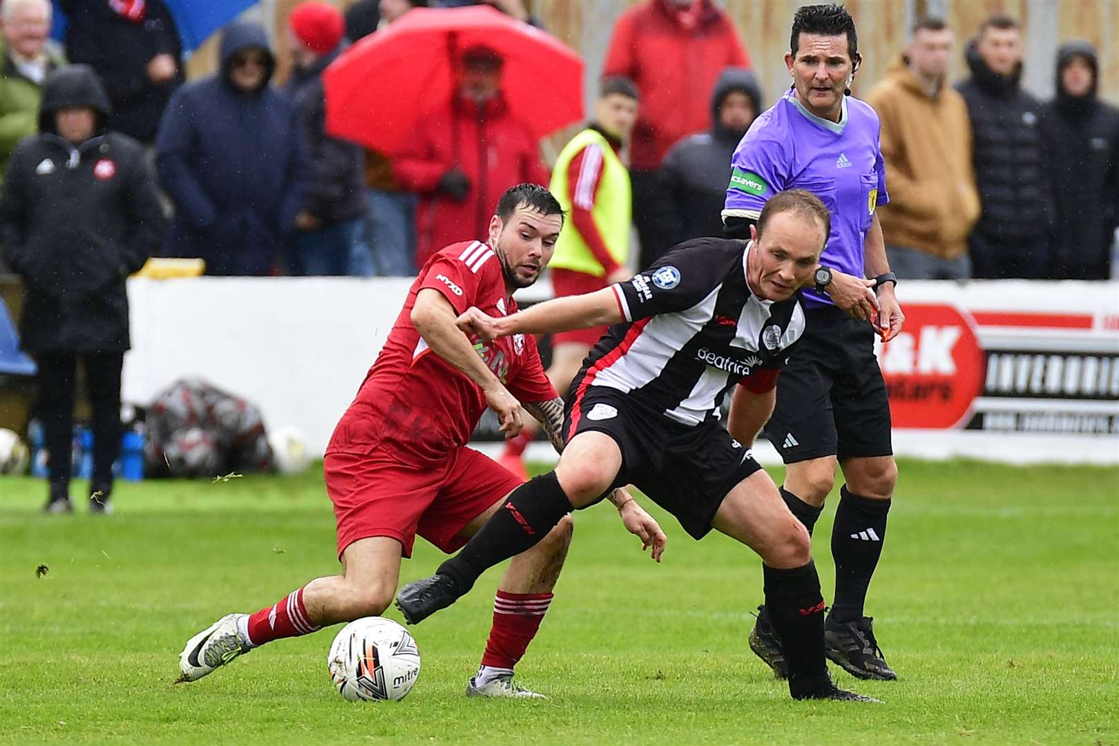 Richard Macadie (Wick Academy) and Niall Kennedy (Lossiemouth) battle for the ball under the watchful eye of referee Billy Baxter. Picture: Mel Roger