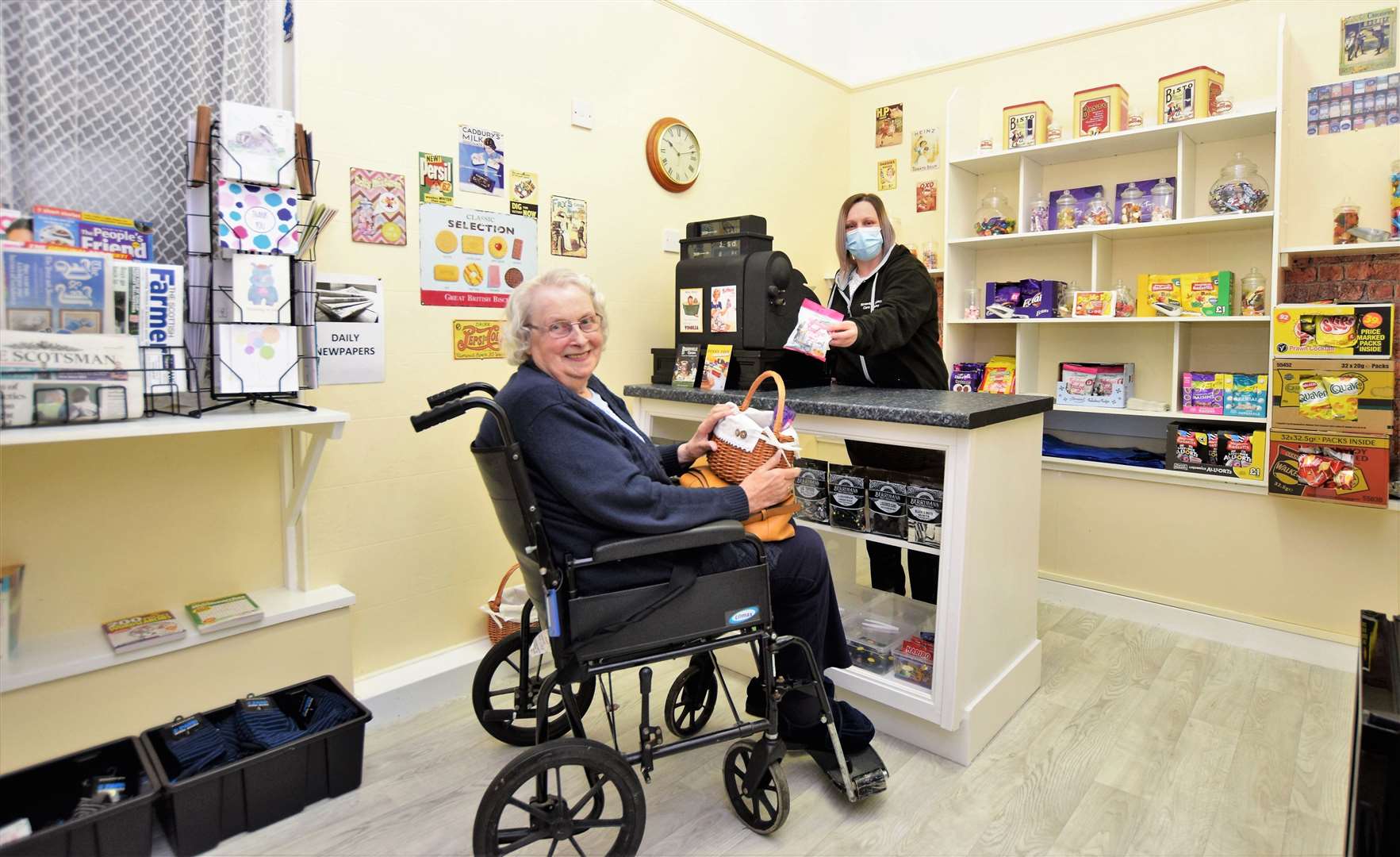 Nettie Innes is the first customer at the new shop at Riverside care home in Wick while lead domestic Lynn Smith operates the till.