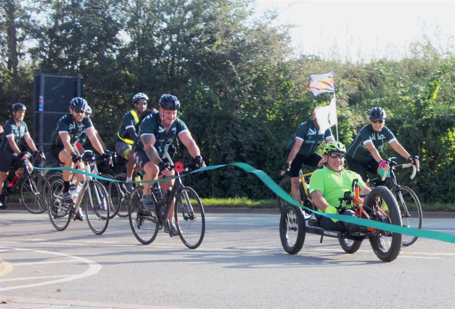 Kev (with the poppy on his handlebars) and other cyclists reach the finishing line at the National Memorial Arboretum. Picture: Louise Coopman