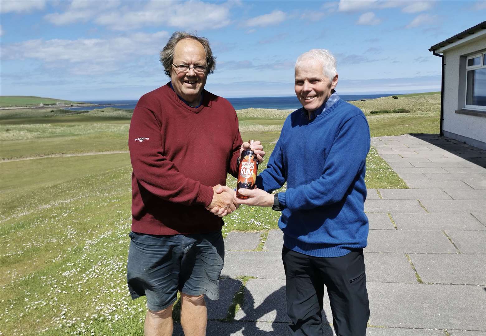 Mike Halliday (left) receives a bottle of North Point spiced rum from Sandy Chisholm for winning nearest the pin in the latest round of the senior Stableford competition at Reay.