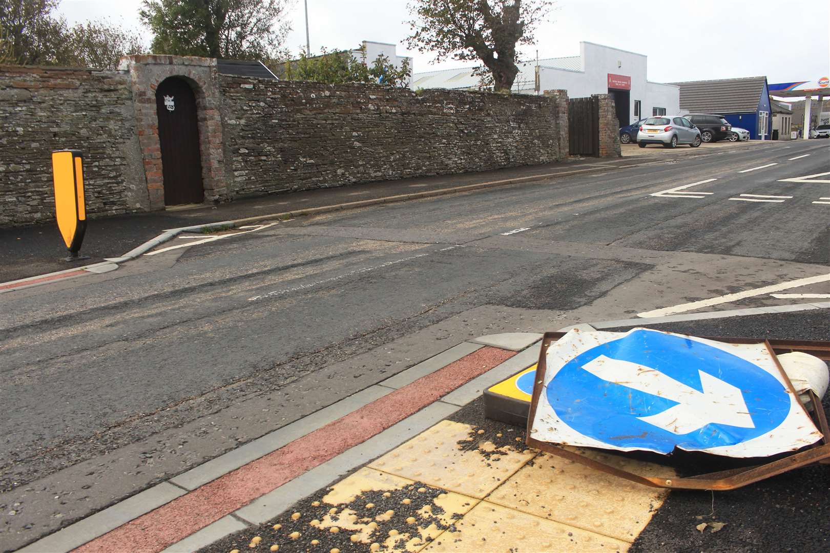 A buckled road sign on top of the flattened bollard.