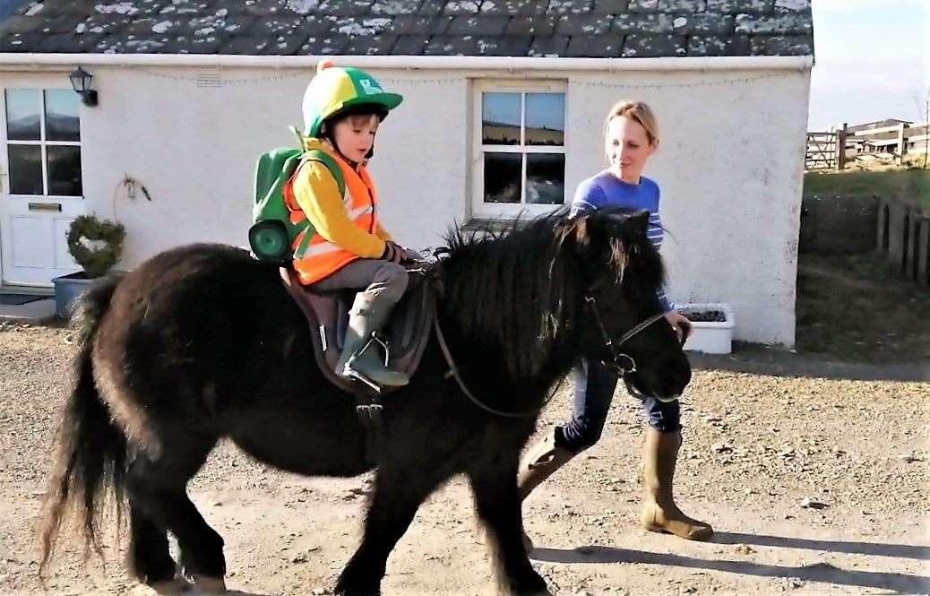 Scye leads Magnus on his pony Vaila round their farm at Spittal.