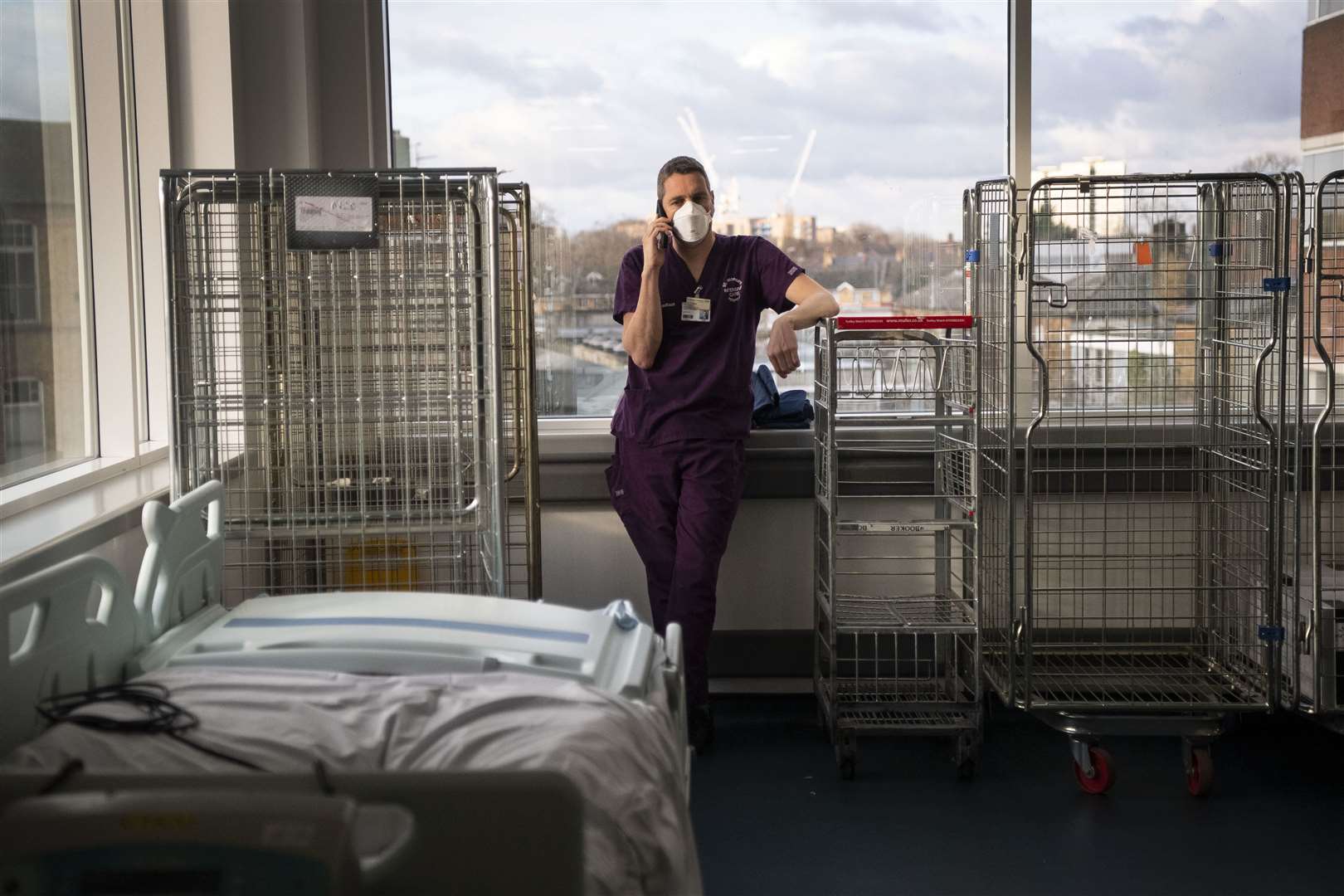 A consultant takes a moment to use his phone in the corridor of the ICU (Victoria Jones/PA)