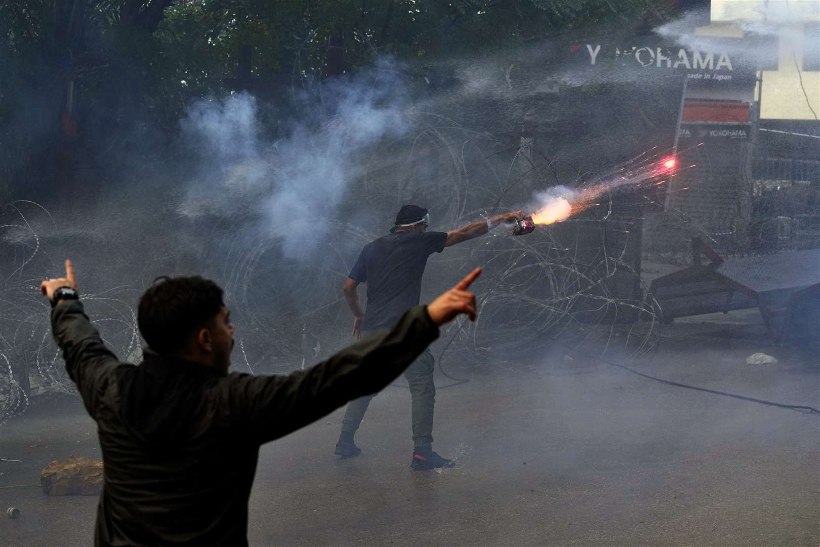 A protester launches fireworks at riot police during a demonstration in solidarity with the Palestinian people in Gaza (Bilal Hussein/AP)