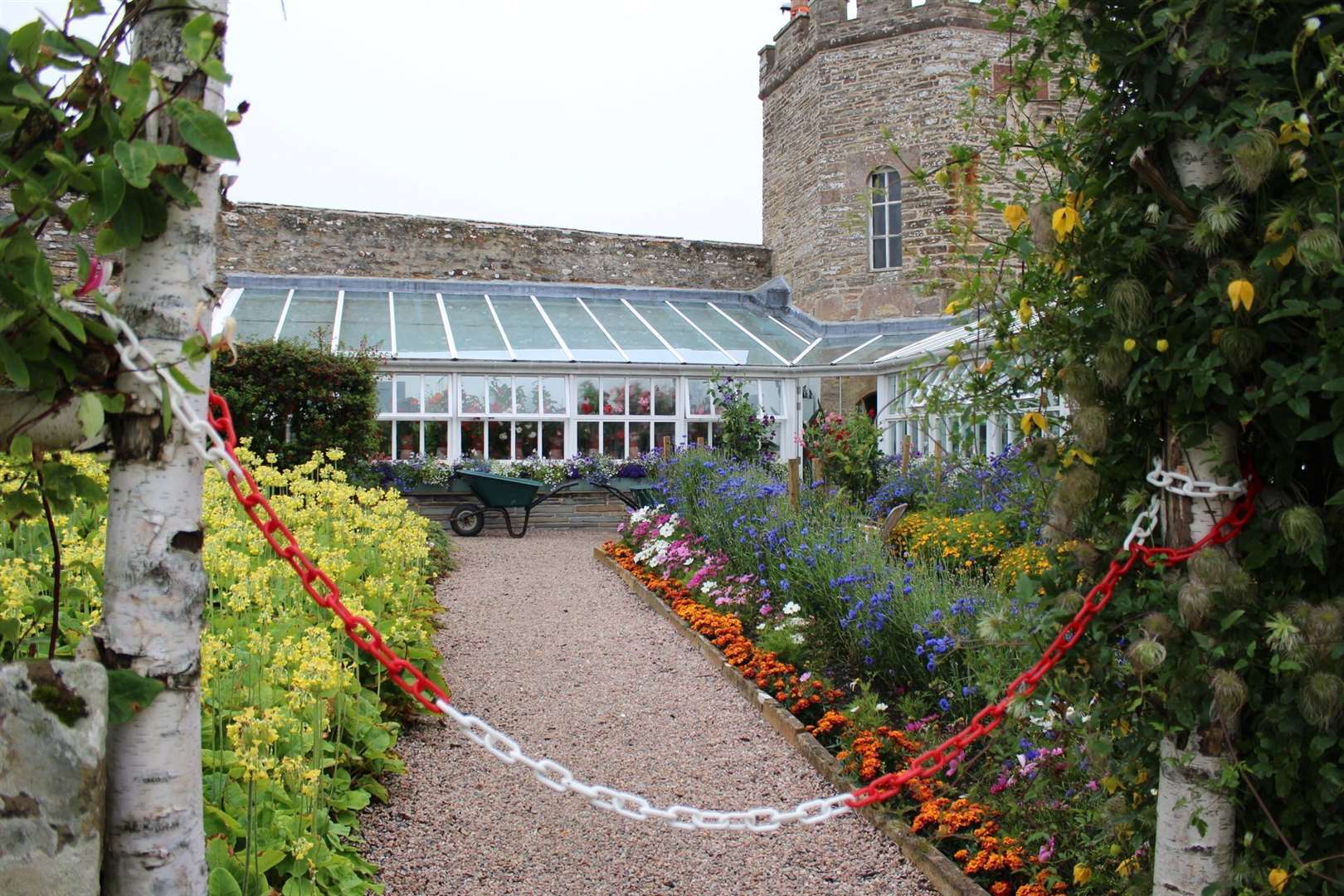 Colourful borders line the path down to the glasshouse in the Gardens of Mey.