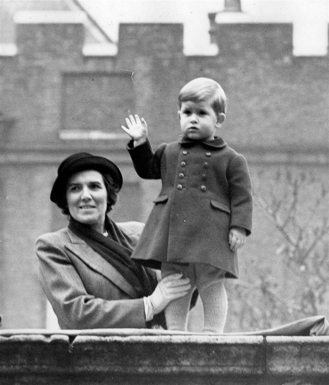 Prince Charles waving from the wall of Clarence House with his nurse Helen Lightbody as his grandparents and Princess Elizabeth travelled to the State Opening of Parliament in 1950 (PA)