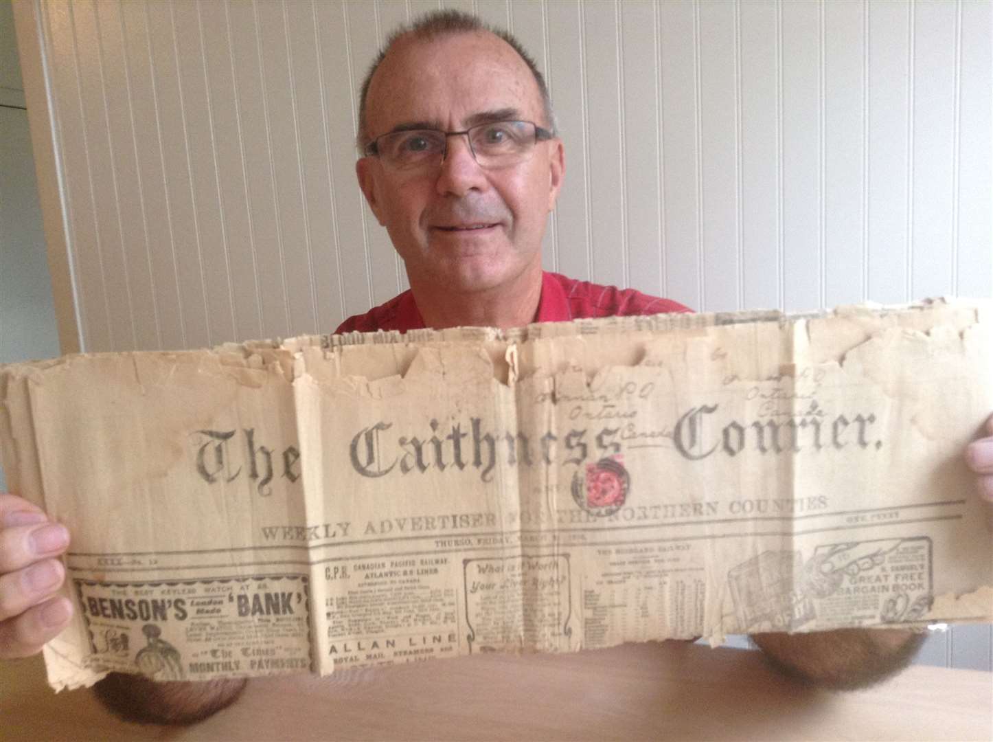 Alexander Sinclair's grandson Wayne on a visit to Caithness in 2013 with the front page of a 1906 Caithness Courier which featured adverts for shipping lines and interest in people going out to Canada.