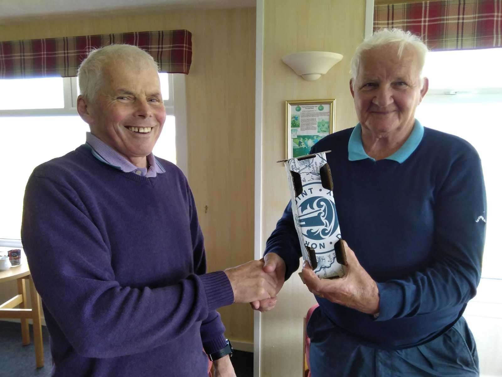 Kenny Farmer Snr (right) receiving a bottle of North Point rum from Sandy Chisholm after winning the nearest-the-pin prize in the senior Stableford competition at Reay.