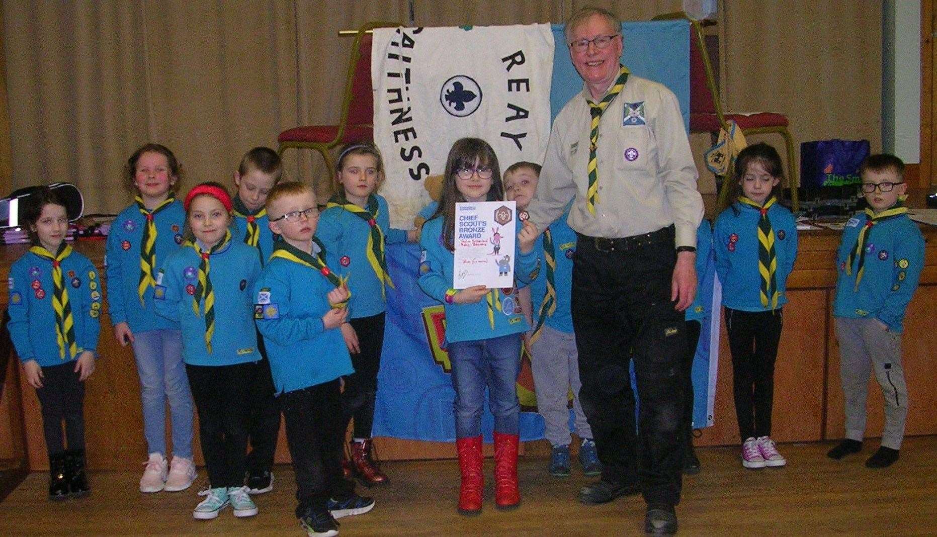 Reay Beaver Scouts look on as Taylor receives the Chief Scout's Bronze Award and the certificate from Beaver leader Ian Pearson.