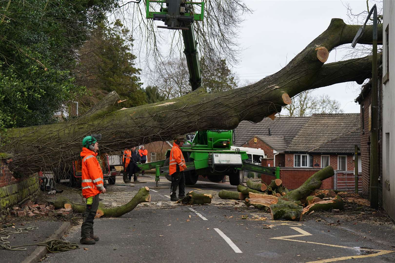 Workmen remove a fallen tree that has damaged the roof of a house in the village of Stanley in Derbyshire (Jacob King/PA)