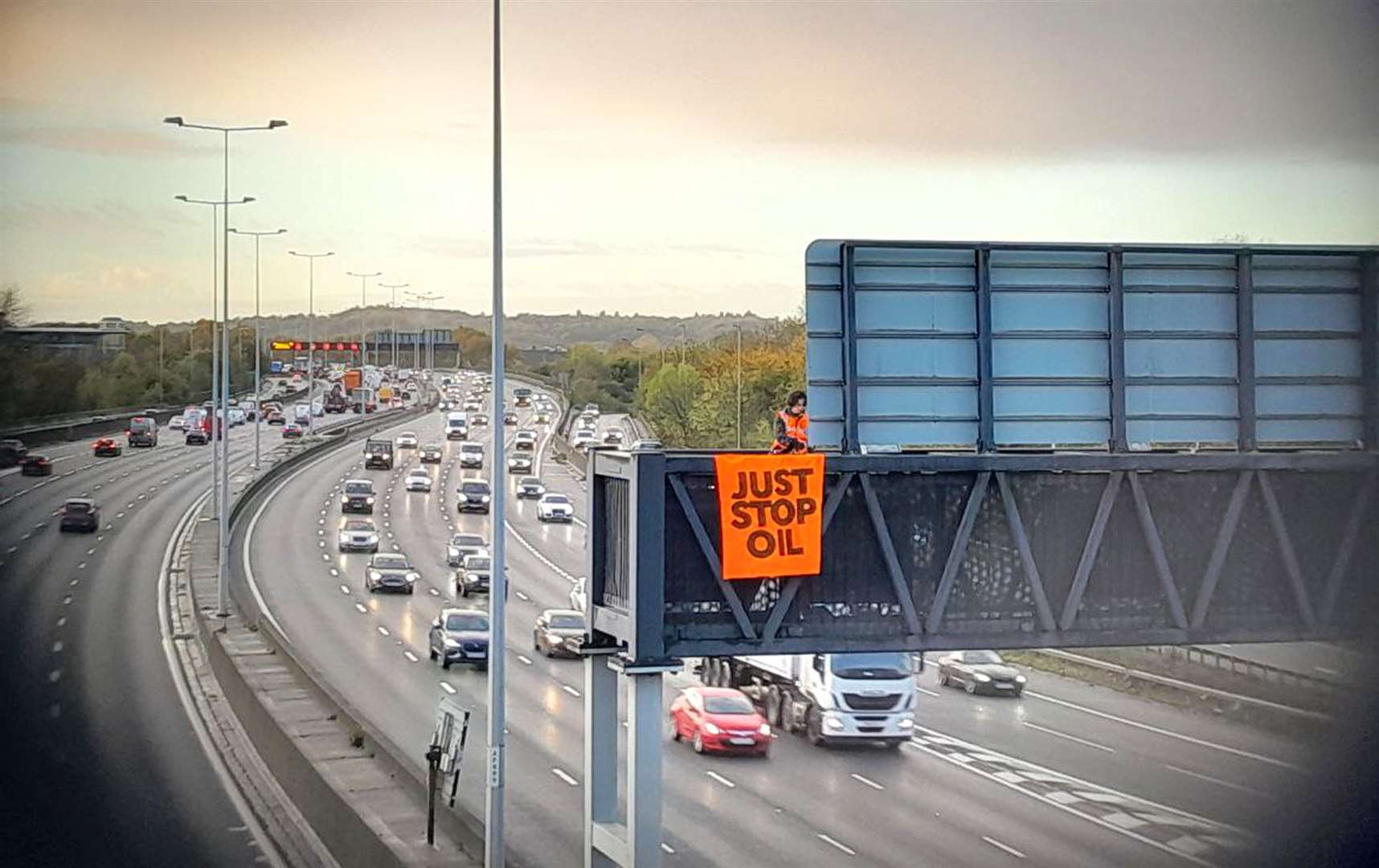 A Just Stop Oil activist on an overhead gantry on the M25 (Just Stop Oil/PA)