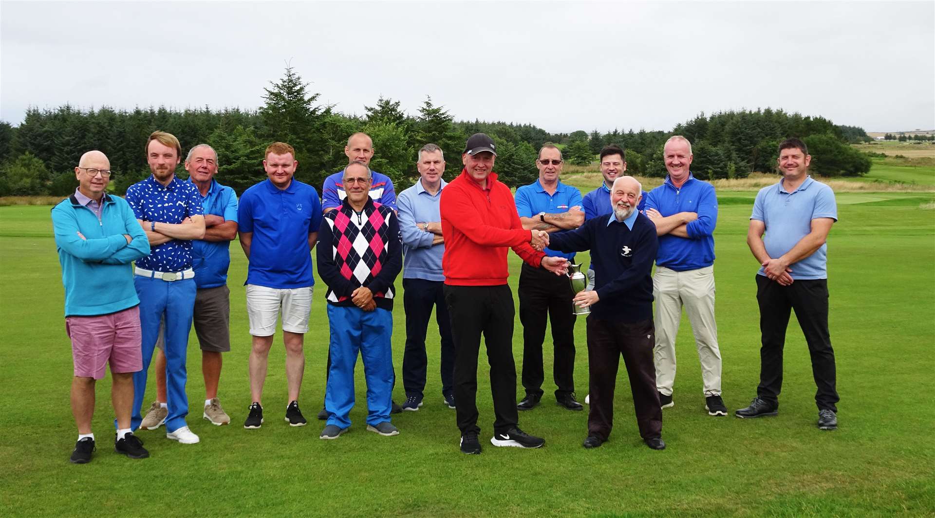 Wolfburn captain Nicky Doherty (red) presenting Dunbar captain Alan Simmonite with the team matchplay trophy.
