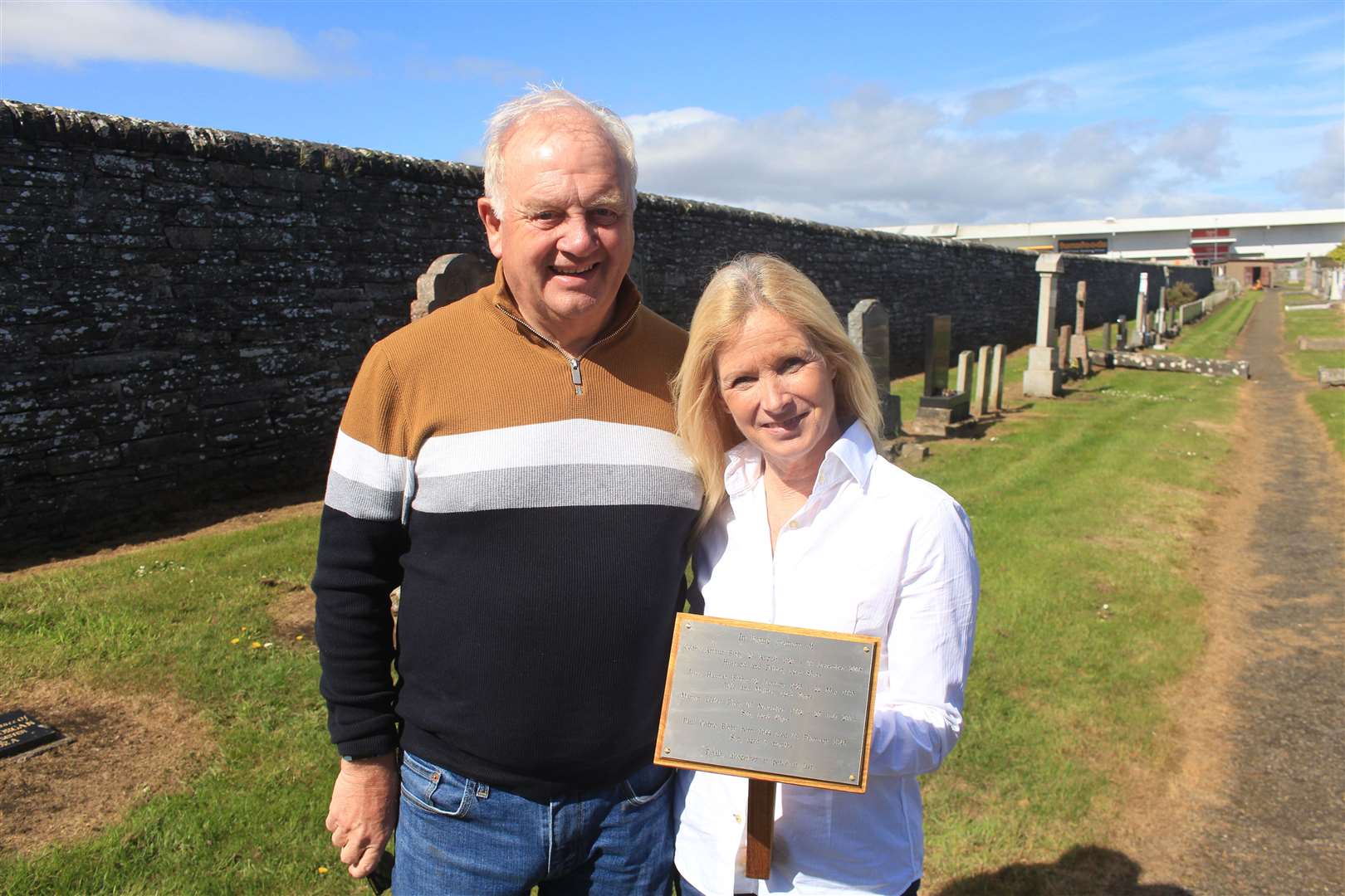 Linda Pirie and husband Alan at Wick cemetery with the engraved plaque containing the names of Cedric, Joyce, Martyn and Paul and the words: 'Finally, altogether at peace at last.' Picture: Alan Hendry