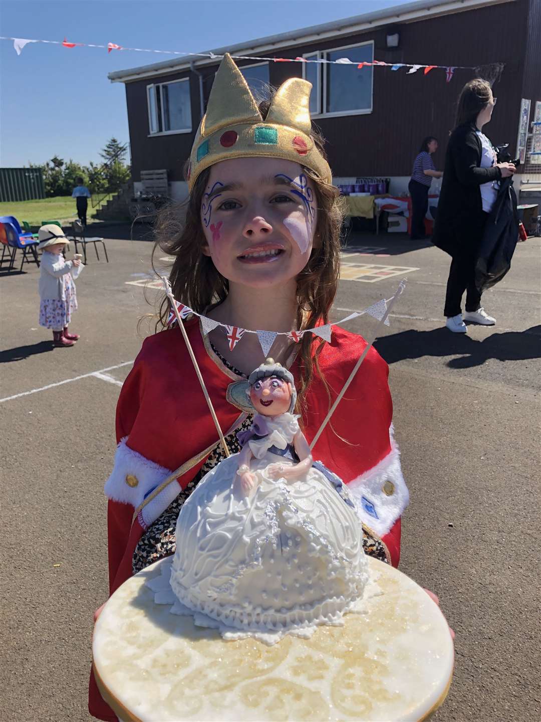 Maci holding a royal cake donated to the school by CC Chocolatier.