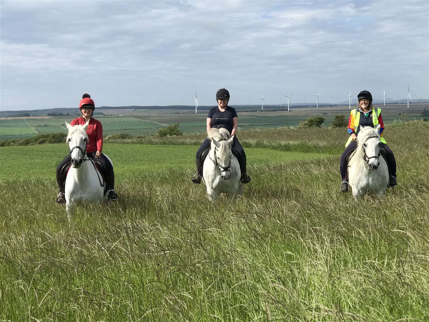 A trio of grey horses and their riders enjoying a hack. From left to right are Eimear Henderson, with Grace, Isabel More and Silver, along with Janet Macleod and Alfie.