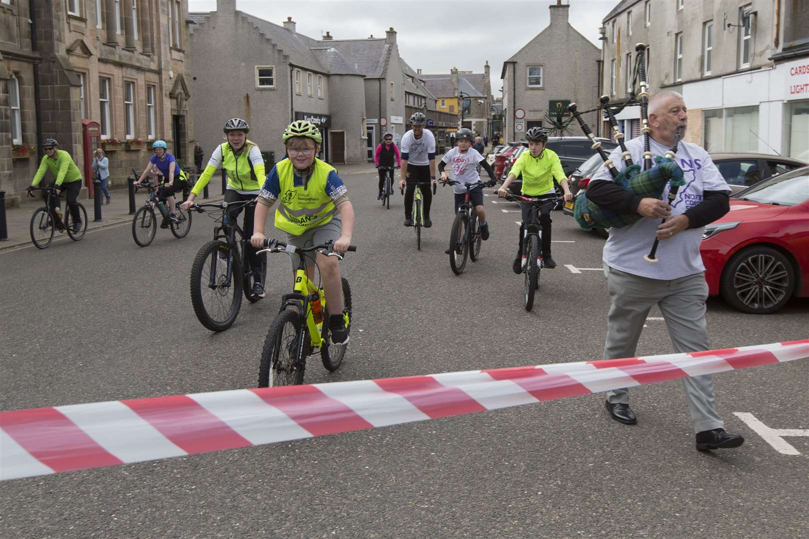 Eight-year-old Aidan Macgruer, followed by family and supporters, is piped towards the finish line in Thurso by his grandad, Willie Larnach. Picture: Robert MacDonald/Northern Studios