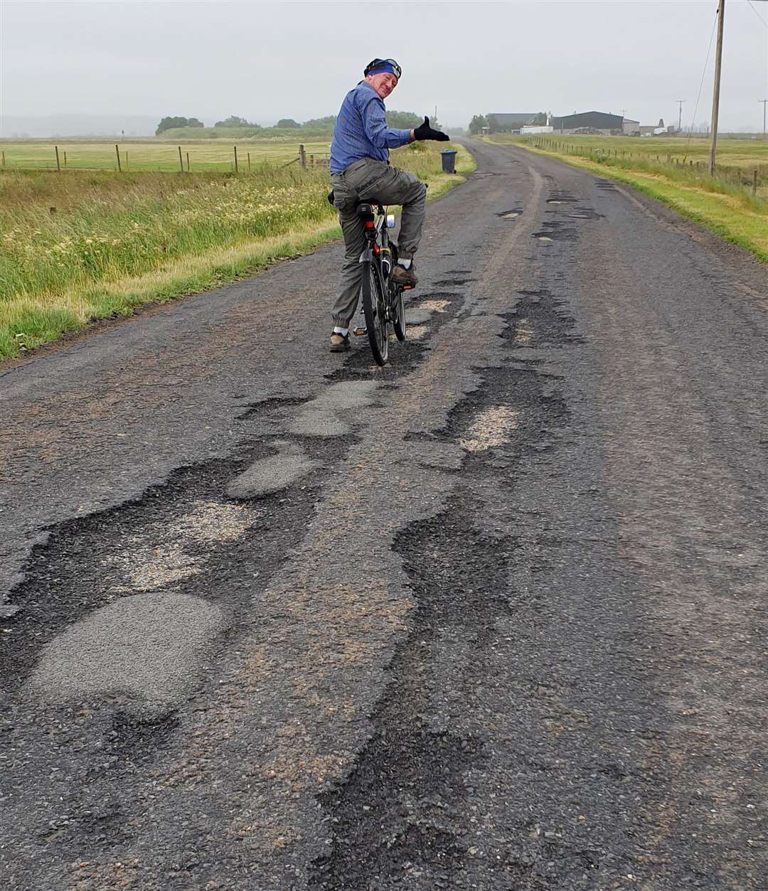 Caithness Roads Recovery campaigner Iain Gregory showing his displeasure at potholes during a bike ride in the Halkirk area.