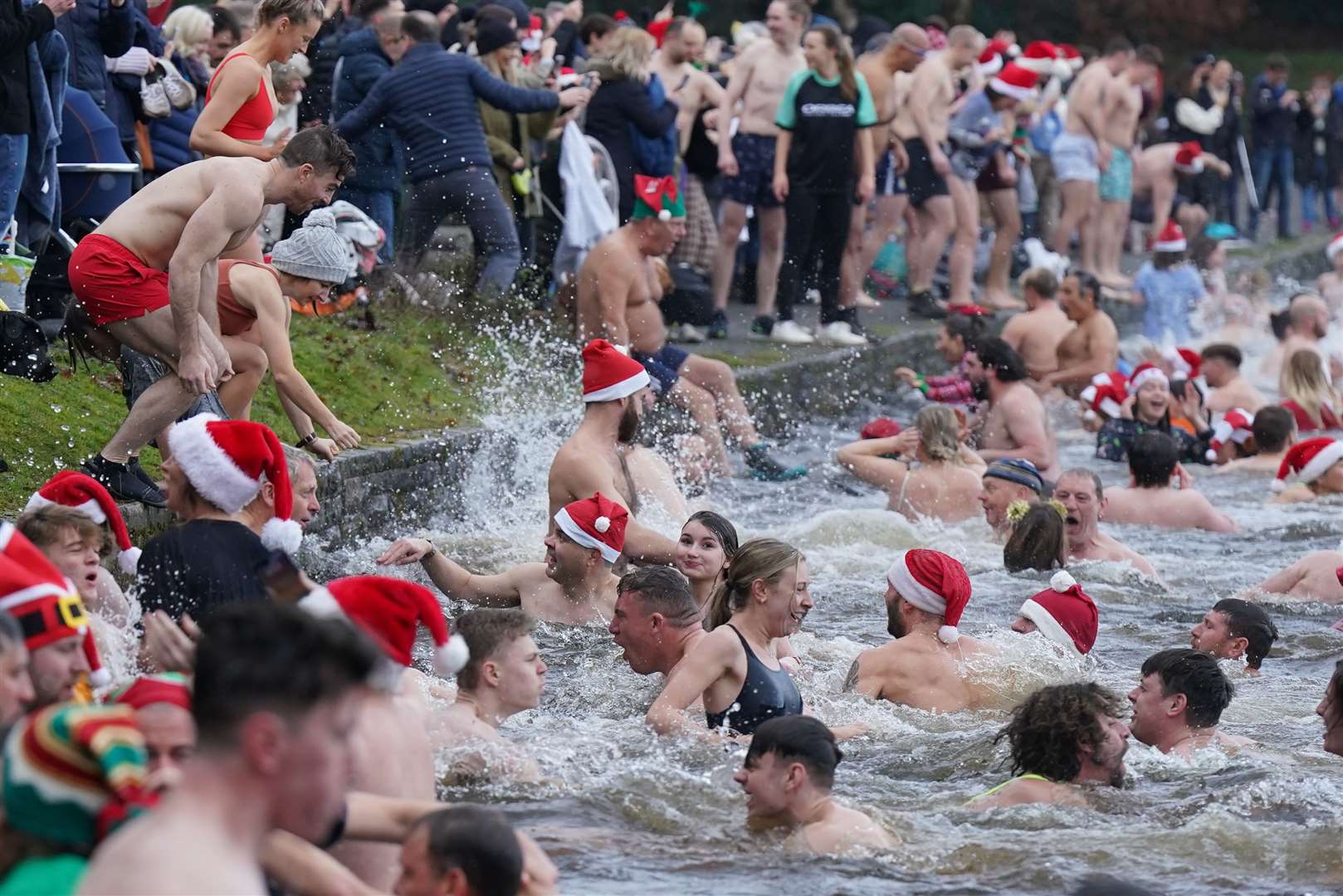 Santa hats featured on many of the hardy swimmers bobbing in the water (Jacob King/PA)