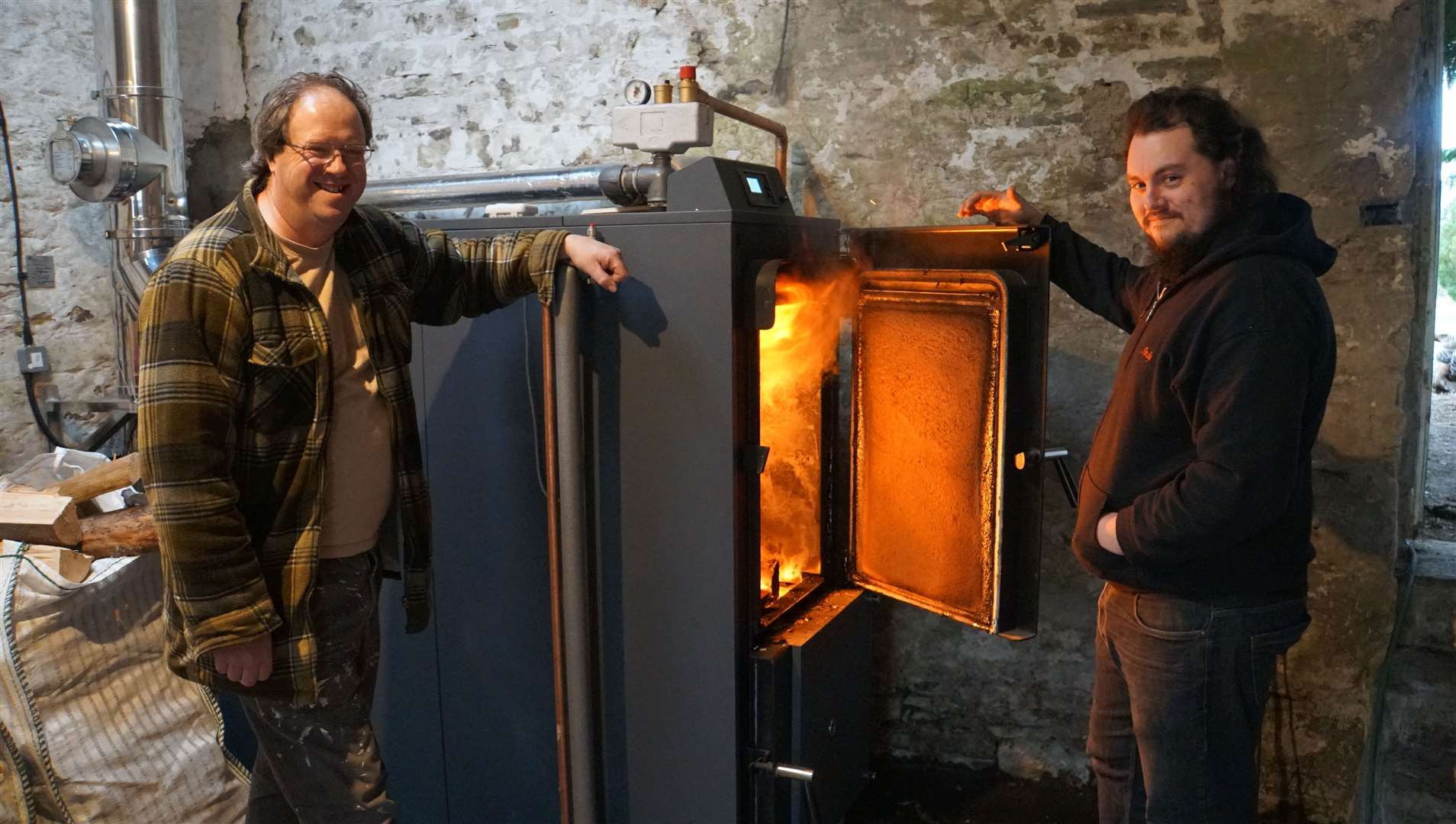 Jason Watts, left, feeds the biomass burner along with his daughter’s partner Andy Sheales.