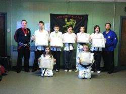 The new black belts are seen here with Mr Tait (extreme left) and Sensei Brian Mearns, from Club Karate in Skye (extreme right) and the black belts who assisted with the grading.