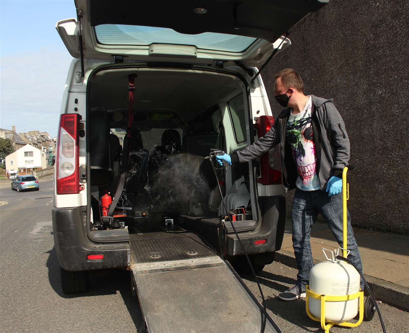 Driver Andrew Sutherland spraying the disinfecting sanitiser inside a Caithness Rural Transport minibus.