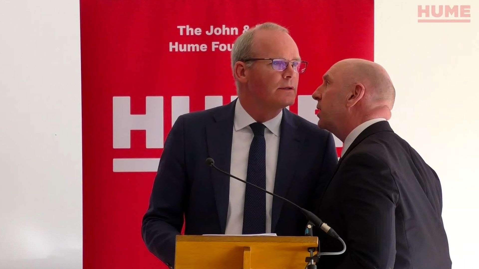 Simon Coveney is ushered from the room due to a security alert in Belfast (Hume Foundation/PA)