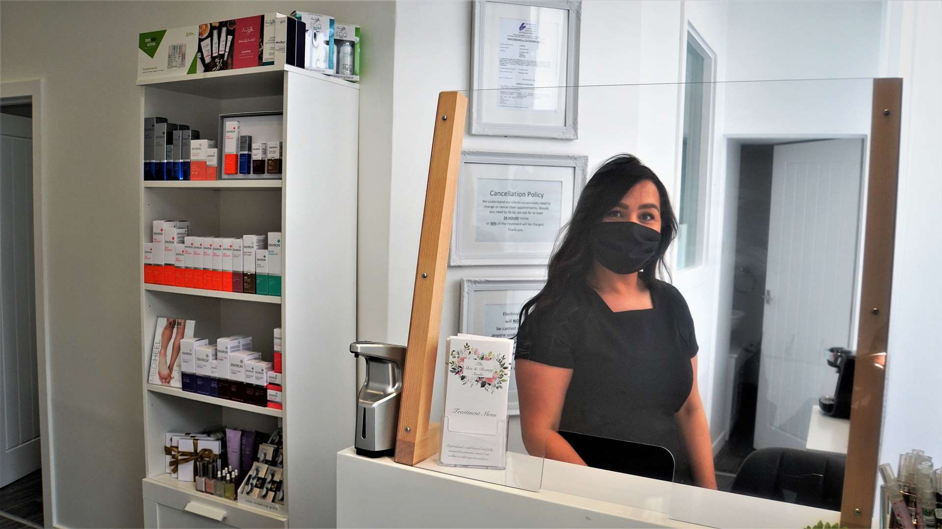 Terren at the till that has been fitted with a protective shield. To the left are the new medical-grade skincare range she now offers.