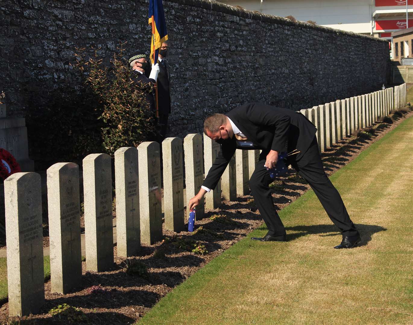 Paul Sutherland, whose mother Cathy is from Queensland, placing an Australian flag on one of the war graves at Wick. Picture: Alan Hendry