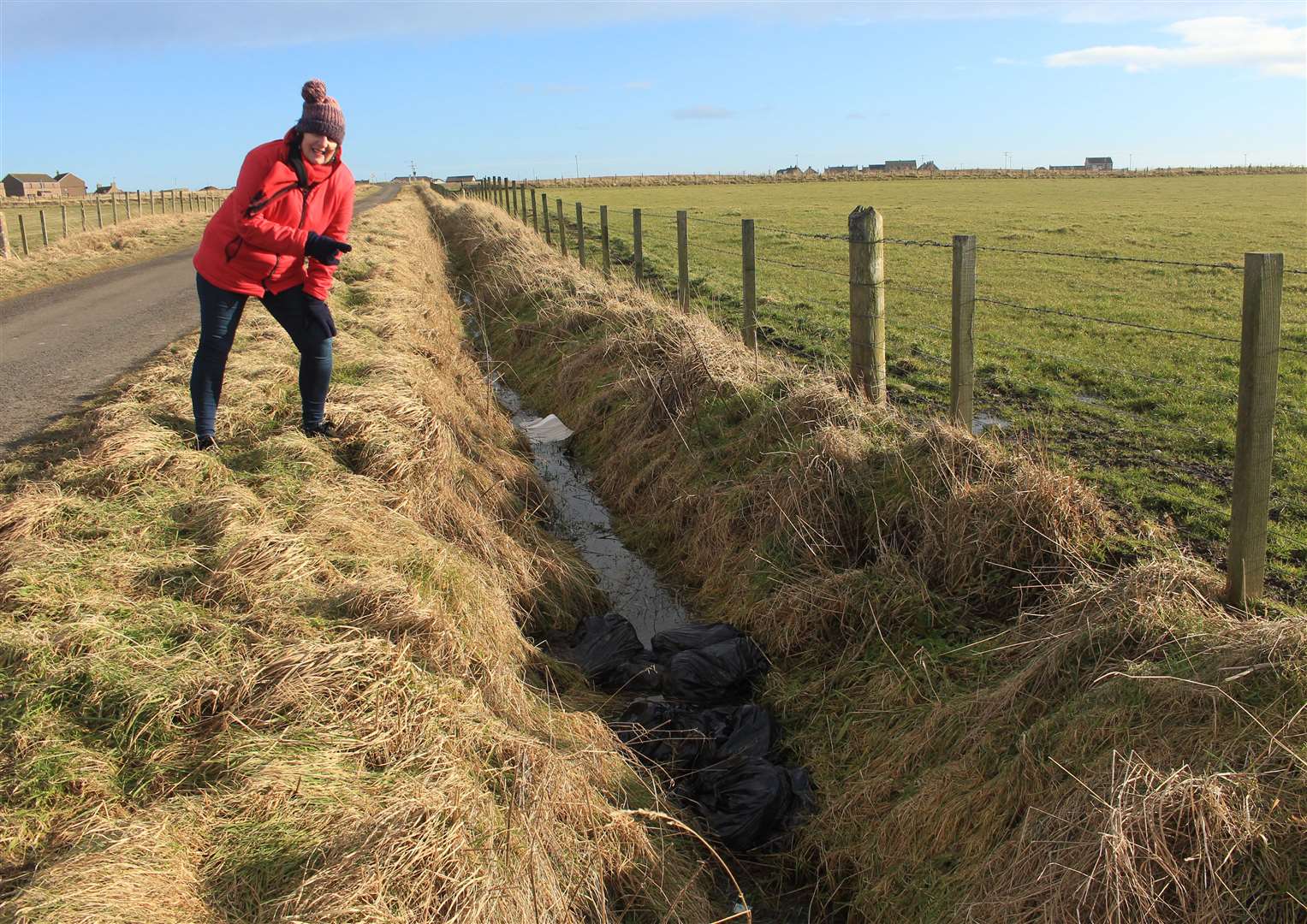 Pat Ramsay pointing to some of the black plastic bags full of soil waste that were dumped in a ditch on the road to Noss. Picture: Alan Hendry