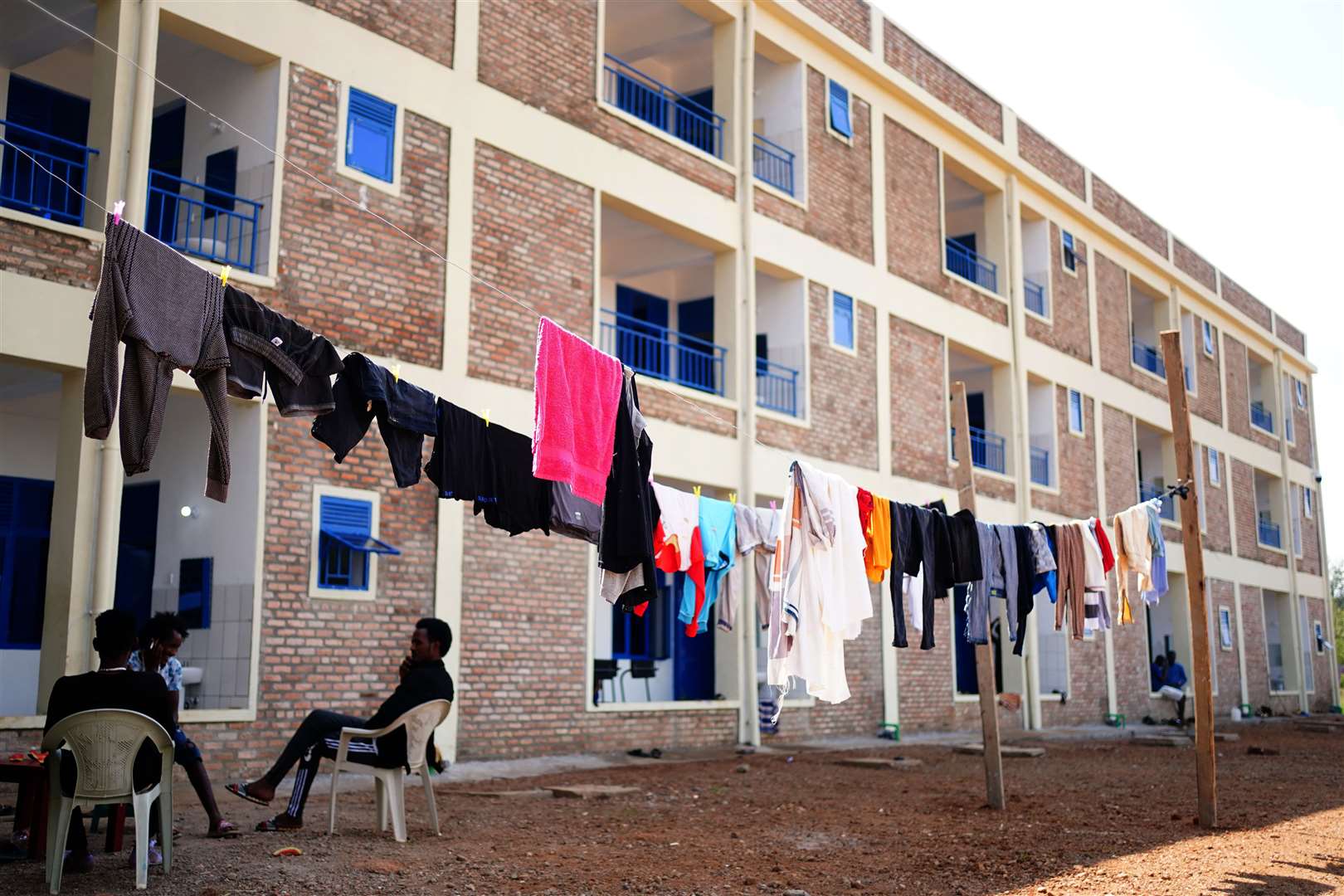 Residents sit outside the new accommodation block at Gashora Refugee Camp Transit Centre (Victoria Jones/PA)